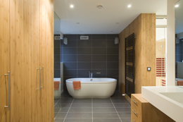 In deze badkamer is gebruik gemaakt van bamboe fineer voor het meubelwerk, HI Macs voor de doucheruimte, en keramische tegels voor de badzone. Hierdoor krijgen de verschillende baadzones een plek in de gehele ruimte. De strategisch geplaatse spiegels vergroten het ruimtelijk effect.
